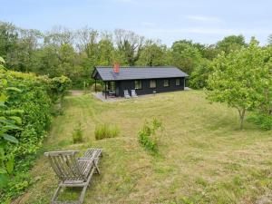 a black house with a bench in front of it at Holiday Home Radica - 400m from the sea by Interhome in Svaneke