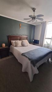 Un dormitorio con una cama grande con ventilador de techo. en Departamento Ñuñoa -Grecia, en Santiago