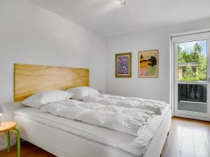 a white bed in a white room with a window at Holiday Home Anelle - 2-5km from the sea by Interhome in Blokhus +17 photos