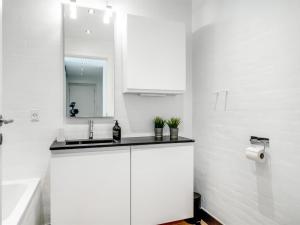a white kitchen with a sink and a mirror at Holiday Home Anelle - 2-5km from the sea by Interhome in Blokhus