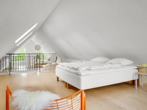 a white bedroom with a bed and a chair at Holiday Home Anelle - 2-5km from the sea by Interhome in Blokhus