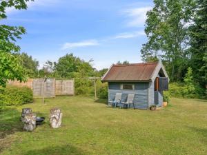 a blue shed with two chairs in a yard at Holiday Home Keke - 2-5km from the sea by Interhome in Eskebjerg