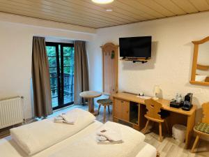 a room with two beds and a desk and a television at Gästehaus Tönisvorst in Tönisvorst