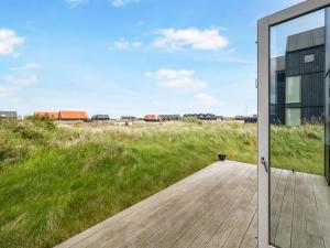 eine Glastür, die zu einer Terrasse mit Blick auf ein Feld führt in der Unterkunft Holiday Home Anita - 575m from the sea by Interhome in Skagen