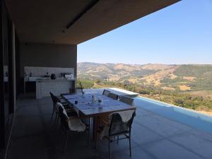 Un comedor con mesa y sillas en un balcón. en Vinicola Spirito, en Espírito Santo do Pinhal