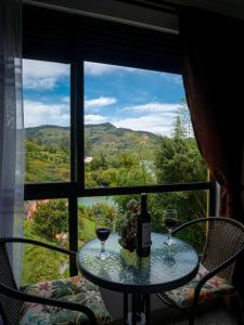 a table with two glasses of wine in front of a window at Descanso Bajo La Piedra Del Peñol in Guatapé