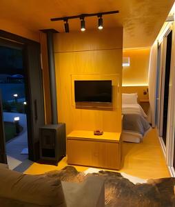 a living room with a tv and a yellow wall at HOSPEDE-SE EM UM CONTAINER AO LADO DE GRAMADO - RS in Igrejinha