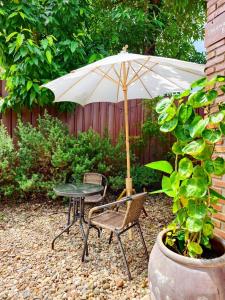 a table and chair with an umbrella in a garden at เติมชีวา Barcafe & Guesthouse in Chiang Rai