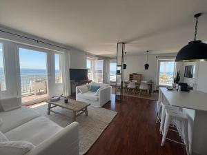 Una sala de estar con muebles blancos y vista al mar. en Le Balcon de Tresmeur, en Bonne Nouvelle