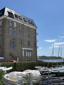 Un gran edificio de ladrillo con barcos en un puerto deportivo. en Le Balcon de Tresmeur, en Bonne Nouvelle