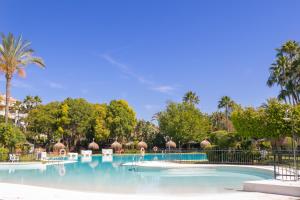 a swimming pool at a resort with palm trees at Apartamento Dama de Noche lll - Puerto Banús in Marbella
