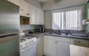 a kitchen with white cabinets and a stove and a sink at One Bedroom Condo with Bay and Ocean Views San Die in San Diego