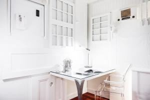 a white kitchen with a glass table and a chair at C3- Hotel Art De Vivre in Quebec City