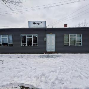 een zwart gebouw met een bord erop in de sneeuw bij Hostel Kuntur in Puerto Natales