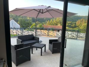 a patio with a table and an umbrella and chairs at Charmant logement avec terrasse et parking sécurisé in Arpajon-sur-Cère