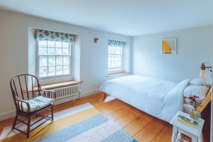 a bedroom with a bed and a chair and windows at Treovis Farm in Callington