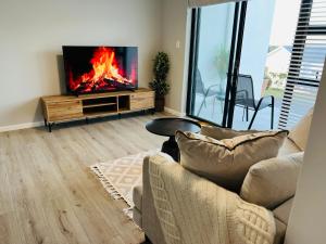 a living room with a couch and a tv with a fire at 27D Homestead View in St Francis Bay