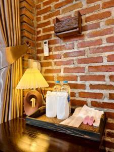 a table with towels and a lamp and a brick wall at เติมชีวา Barcafe & Guesthouse in Chiang Rai