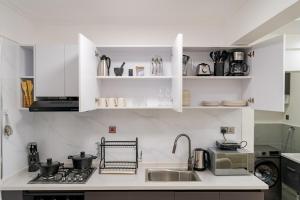 a kitchen with white cabinets and a sink and a stove at Casa Inikas -Luxurious 1 bedroom Marina Bay in Nairobi