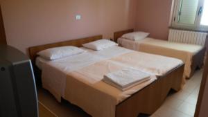 two beds in a small room with a television at Hotel La Pineta in Spilinga