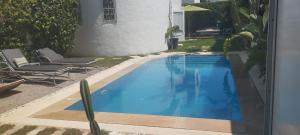 une grande piscine bleue à côté d'une maison dans l'établissement VILLA de CHARME A HAMMAMET TUNISIE, à Hammamet