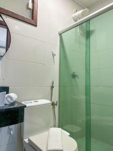 a bathroom with a toilet and a glass shower at Pousada Camburi in Morro de São Paulo