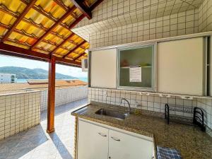 a kitchen with a sink and a large window at Cobertura Pé na Areia Vista Mar Churrasqueira 12 Pessoas in Arraial do Cabo