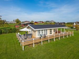 a house with a large wooden deck in a field at Holiday Home Arton - 300m from the sea by Interhome in Ebberup