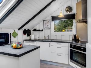a kitchen with white cabinets and a window at Holiday Home Liljana - 30km from the sea by Interhome in Toftlund +9 photos