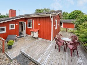 a deck with a red house with a table and chairs at Holiday Home Anline - 900m to the inlet by Interhome in Tarm