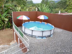 a hot tub with two umbrellas next to a fence at Cabaña Renaciendo in Turrialba