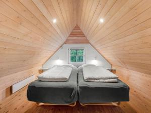 a bed in a room with a wooden ceiling at Holiday Home Dorris - 4-3km from the sea by Interhome in Nørre Nebel +28 photos