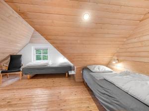two beds in a room with wooden walls at Holiday Home Dorris - 4-3km from the sea by Interhome in Nørre Nebel