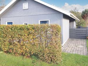 ein Haus mit einer Hecke vor einem Gebäude in der Unterkunft Holiday Home Remo - 990m to the fjord by Interhome in Hemmet