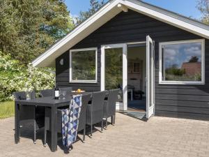 a black shed with a table and chairs on a patio at Holiday Home Ingward - 300m to the fjord by Interhome in Tarm