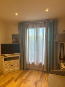 a living room with a television and a large window at Studio in Cogolin