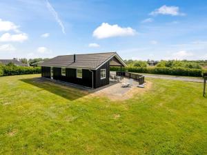 a black house with a large grassy yard at Holiday Home Saara - 700m to the inlet by Interhome in Tarm