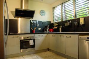 una cocina con electrodomésticos de acero inoxidable y un reloj en la pared en Eden Sea Villa, en Pointe-Noire