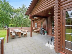 una cabina in legno con patio, tavolo e panche. di Holiday Home Frederica - 30km from the sea by Interhome a Toftlund
