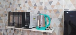 a microwave sitting on a shelf next to a coffee pot at Flat a 4 minutos da basílica in Aparecida