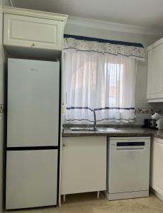 a kitchen with a white refrigerator and a window at Roger's house frente al mar en Alicante in Gran Alacant