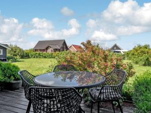 a table and chairs on a deck with a yard at Holiday Home Gudmunda - 200m to the inlet by Interhome in Skjern