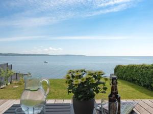 a table with a bottle of beer and a vase with a plant at Holiday Home Herewardus - 10m to the fjord by Interhome in Børkop