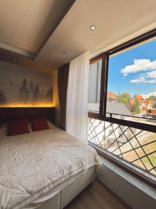 a bedroom with a bed and a large window at Evergreen Lux in Kopaonik