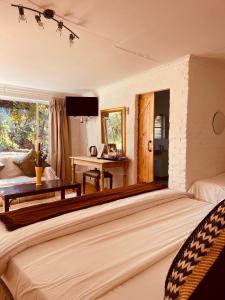 Die Ou Pastorie في هارتبيسبورت: غرفة نوم بها سرير كبير وطاولة