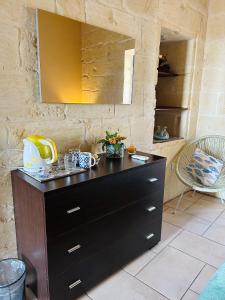 a black dresser in a room with a mirror at 250 yo Tal-Bambinu Boutique Farmhouse in Xagħra