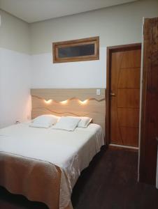 a bedroom with a large white bed with lights on it at chale comandatuba in Água Boa