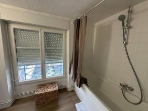 a bathroom with a bath tub and a window at Beau Repère Coulommiers 77 in Coulommiers