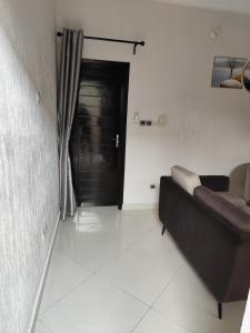 a living room with a couch and a black door at SIKA Résidences BJ in Cocotomey