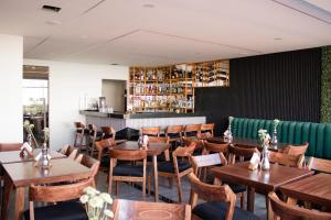 ein Restaurant mit Holztischen und -stühlen und einer grünen Couch in der Unterkunft Hotel Del Centro HC in Tepatitlán